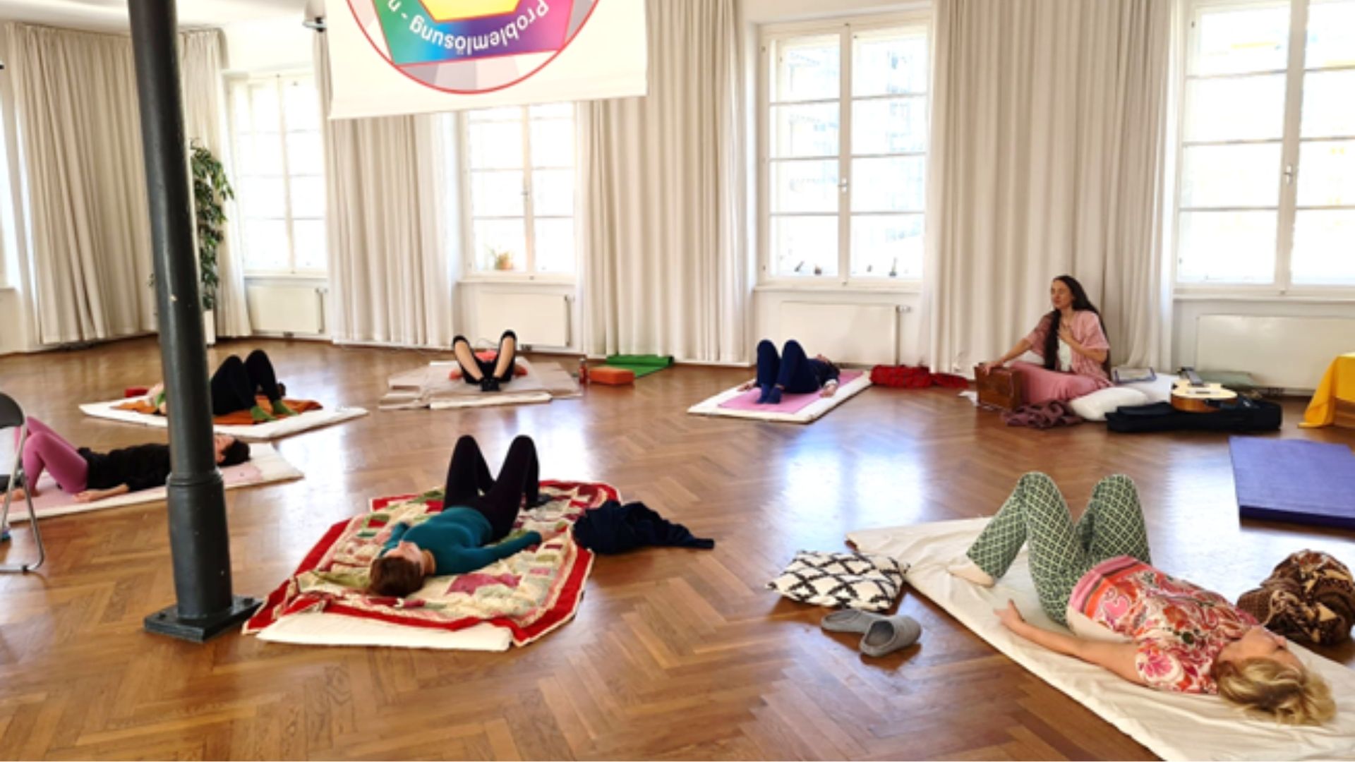 6 Damen auf Yogamatten im Festsaal des Schloss Freiberg beim TRE Tension Release Exercise entspannt am Rücken liegend